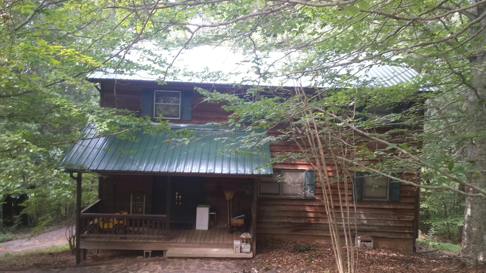 Green metal roof and covered porch on a log cabin in East Springfield