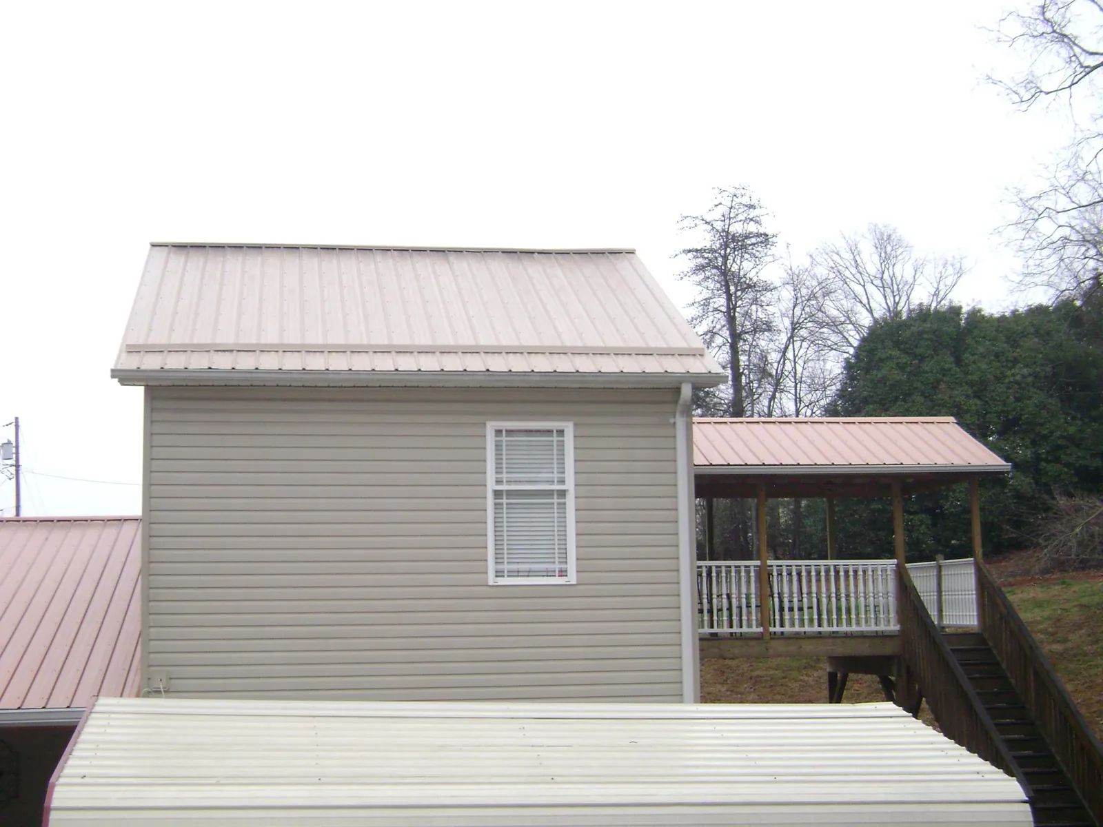 Tan metal roofs on a two story addition and attached porch, from a Roof Replacement job in East Springfield