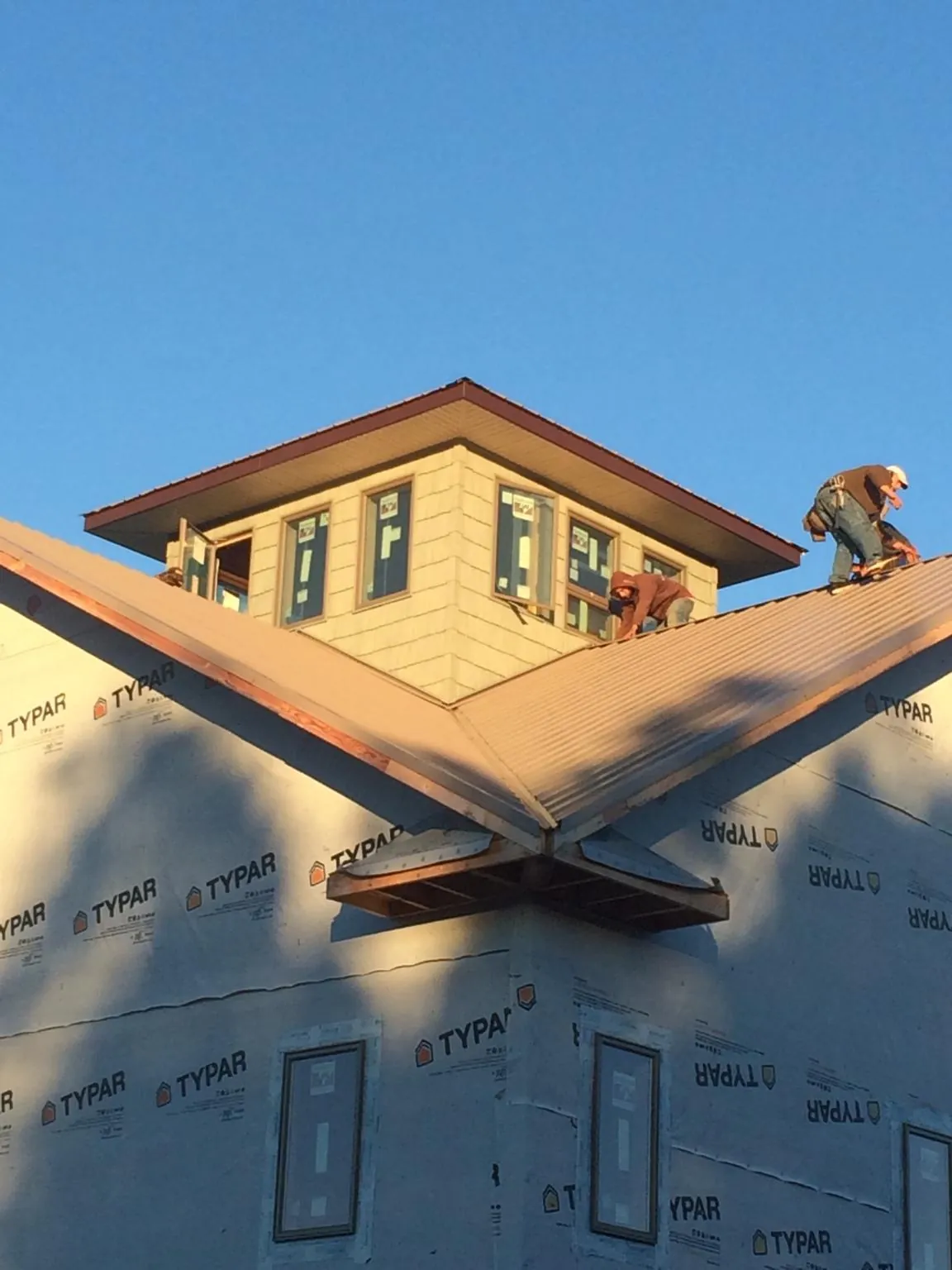 Roofers working around a rooftop cupola on a new metal roof at sunset — Roof Waterproofing in East Springfield by Roofing Brothers